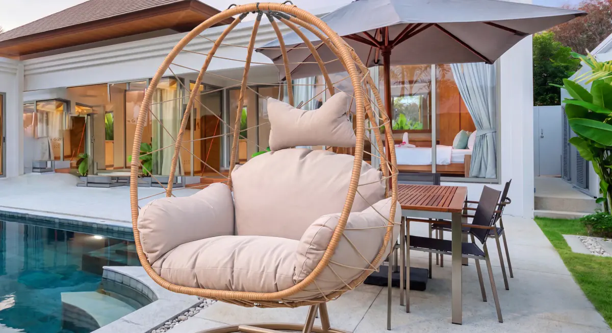 Woven hanging egg chair on a poolside patio